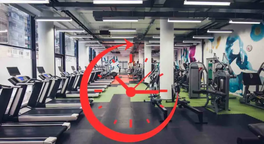 Una palestra moderna con tapis roulant e macchine per il fitness. Un grande orologio rosso sovrapposto suggerisce gli orari migliori per andare in palestra.