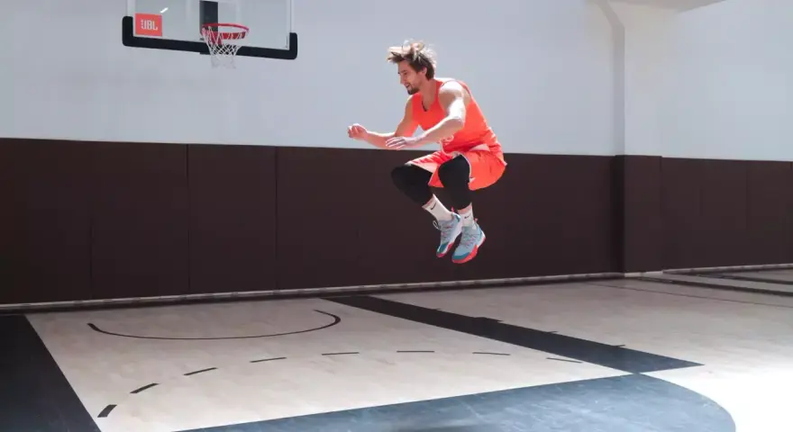 Atleta in aria, in pieno allenamento contro resistenza, su un campo da basket.