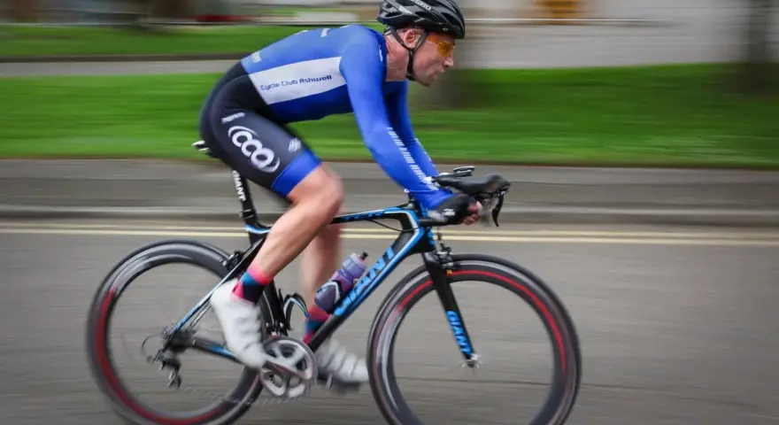 Ciclista in gara, i suoi muscoli delle gambe lavorano intensamente per spingere i pedali.
