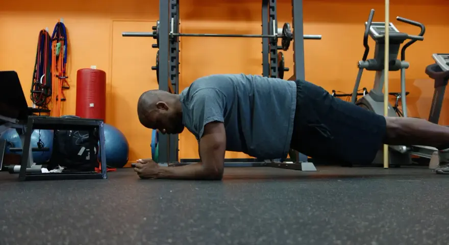Uomo in posizione di plank, allenamento per i muscoli del core in palestra.