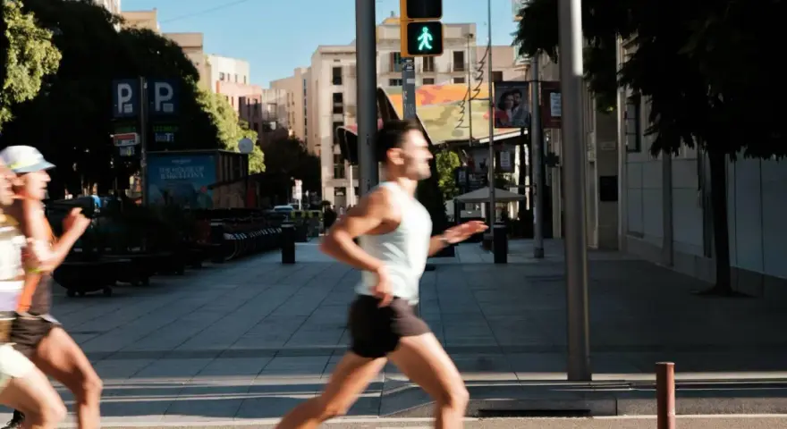 Corridori in città, un uomo corre con un semaforo pedonale verde. Il **talk test** è superato, respira bene.