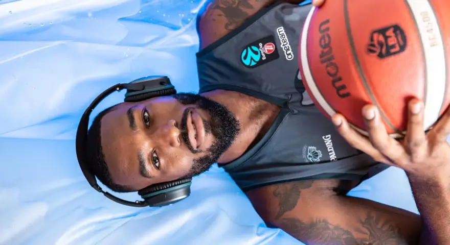 Giocatore di basket con cuffie e pallone, pronto per la preparazione fisica.