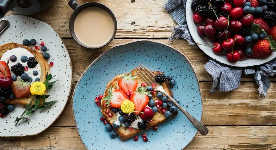 Toast con frutta fresca e yogurt, una colazione energetica per sportivi. Frutti di bosco, fragole e ciliegie per iniziare la giornata con vitalità.