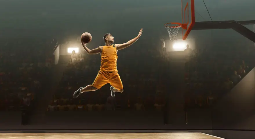 Un giocatore di basket in aria, pronto a schiacciare, sembra quasi fermo nel tempo per riprendere fiato prima del grande momento.