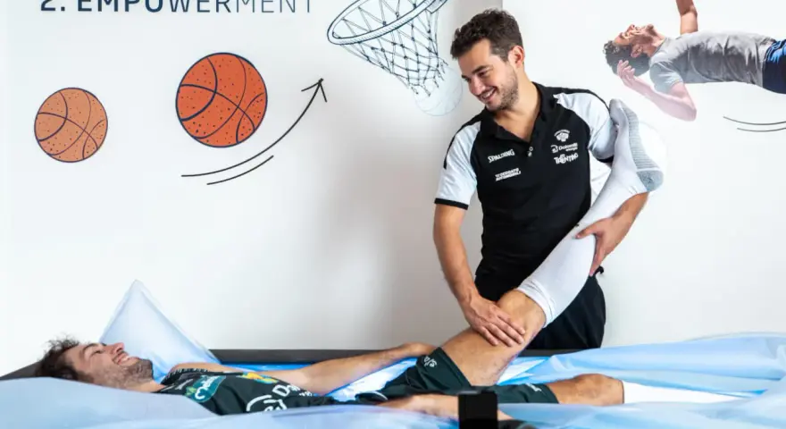 Un atleta in recupero, sdraiato in una vasca, riceve assistenza da un terapista. Un'immagine che simboleggia la ripresa e la migliore prestazione sportiva.