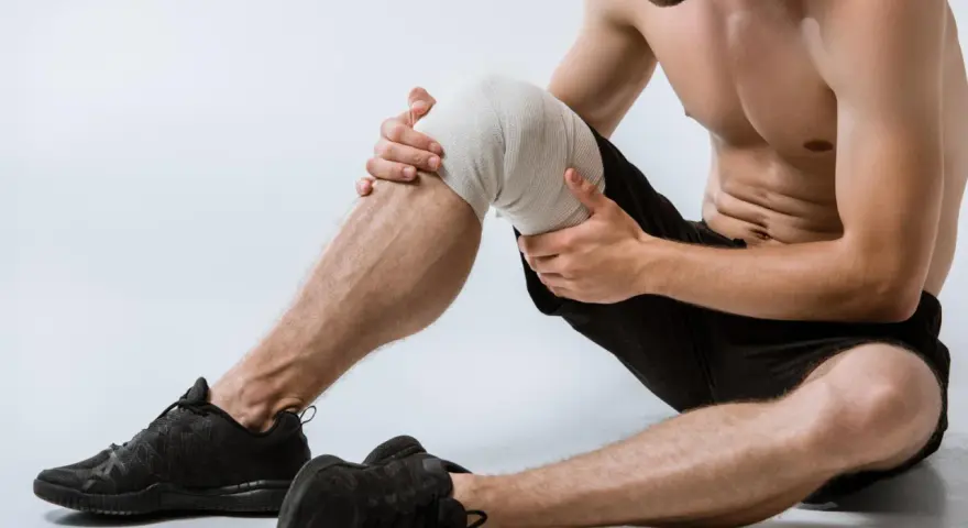 Uomo con ginocchio fasciato, pronto per esercizi per menisco lesionato.