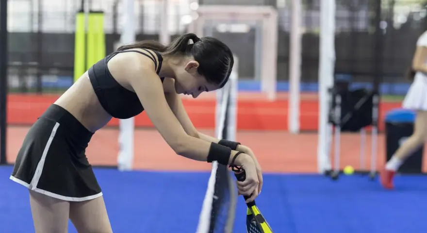 Giocatrice di padel esausta, forse cerca rimedi naturali per il dolore all'anca dopo l'allenamento.