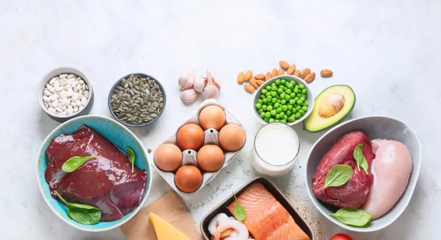 Varietà di alimenti ricchi di zinco: fegato, carne rossa, pollo, salmone, gamberi, uova, fagioli, semi di zucca, piselli, mandorle, avocado, formaggio, latte, aglio e grano saraceno.