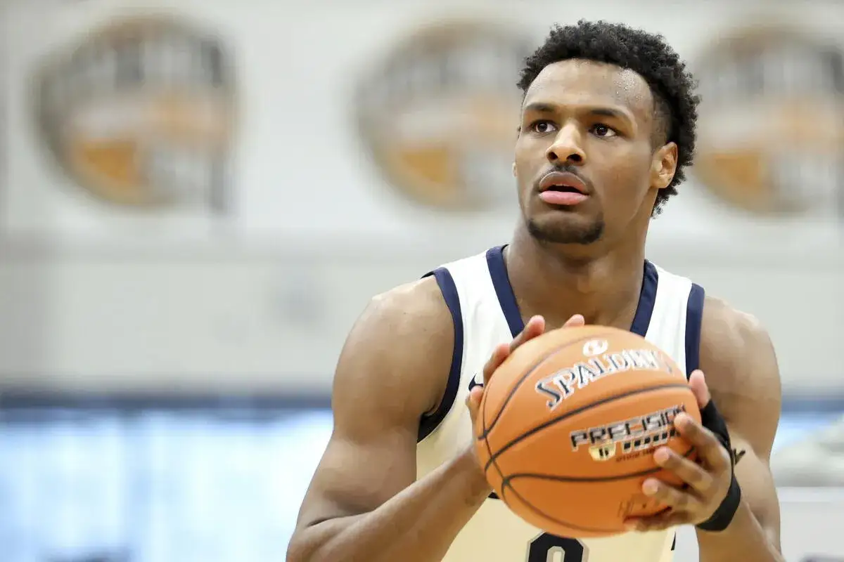 Basketball player in uniform holding a Spalding ball, looking up.