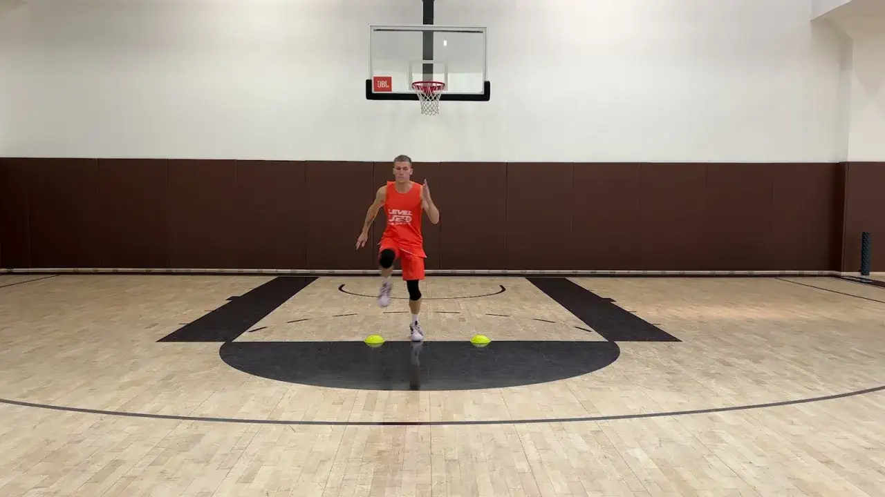 Giovane atleta in campo da basket esegue esercizi per il recupero muscolare gambe, con coni gialli a terra.