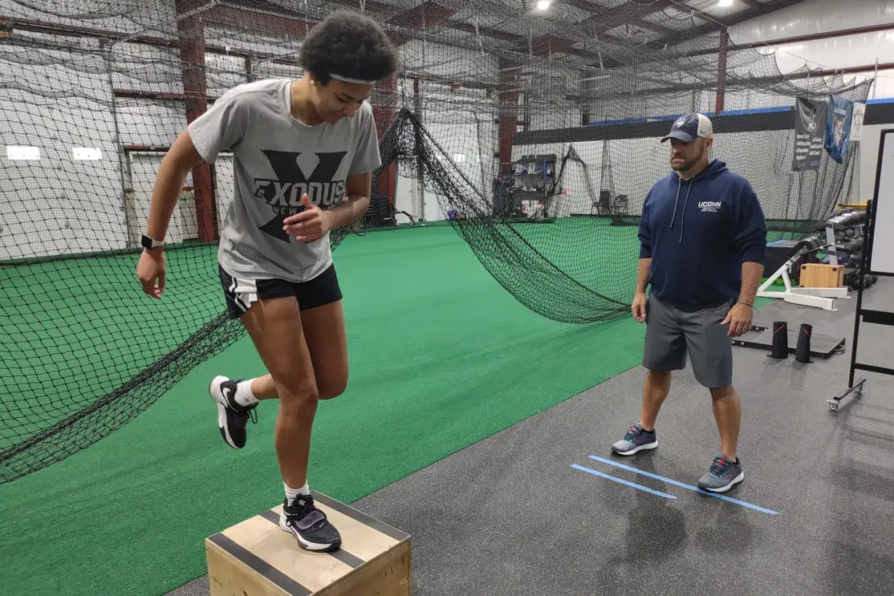 Allenamento per prevenire i muscoli schiena infiammati: sintomi e prevenzione. Atleta esegue step-up, coach osserva.