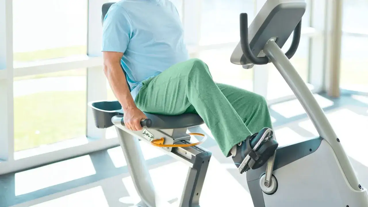 Uomo in riabilitazione su cyclette dopo protesi al ginocchio, con movimenti dolci per recuperare la mobilit&agrave;.