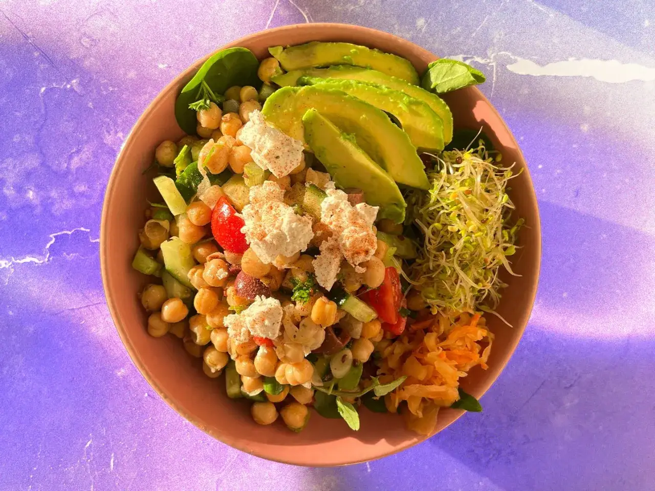 Insalata ricca di proteine con ceci, avocado, pomodorini, cetrioli e germogli. Un'idea fresca per le tue ricette con proteine.