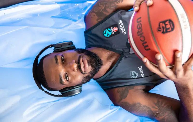 Giocatore di basket con cuffie e pallone, pronto per la preparazione fisica.